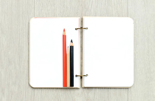 Otwarte pustego notatnika z Kolorowe kredki na drewnianym stole — Zdjęcie stockowe