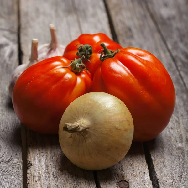 Tomaten, ui en knoflook op tafel — Stockfoto