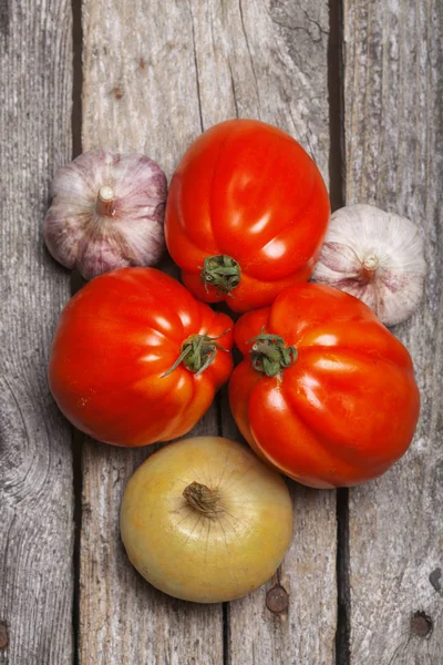 Tomaten, ui en knoflook op tafel — Stockfoto