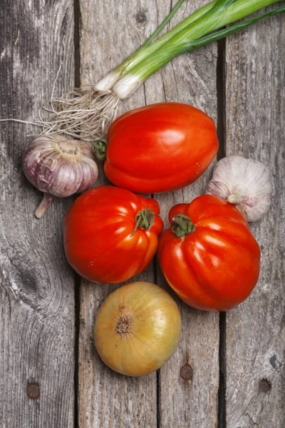 Tomaten, ui en knoflook op tafel — Stockfoto