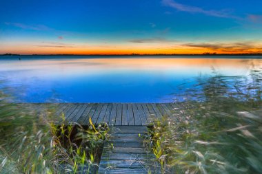 Uzun pozlama görüntü, mavi günbatımı sona kıyısında bir iskelesi