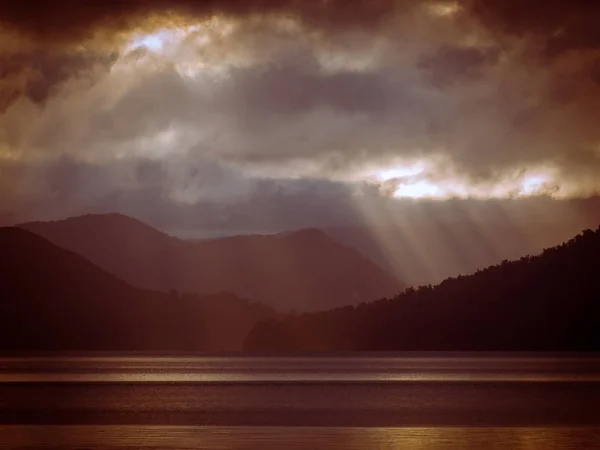 Raios de sol brilhando através de nuvens sobre nevoeiro lago de montanha em vinta — Fotografia de Stock