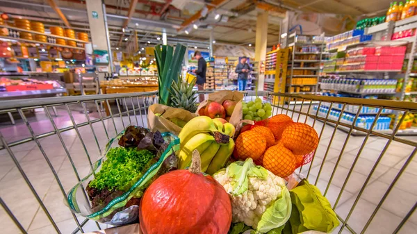 Einkaufswagen mit Menschen, die im Hintergrund einkaufen — Stockfoto