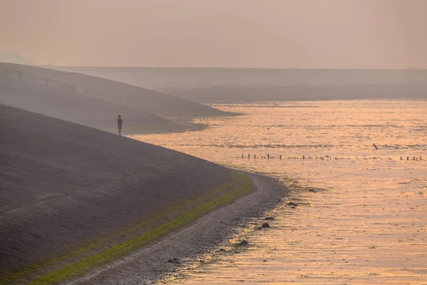 Persona observando atardecer desde el dique de mar en neblina naranja —  Fotos de Stock