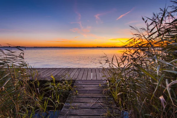 Zonsondergang over houten promenade aan de oever van een meer — Stockfoto