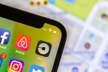 Uber app logo üstünde hareket eden telefon ile arka planda sokak haritası