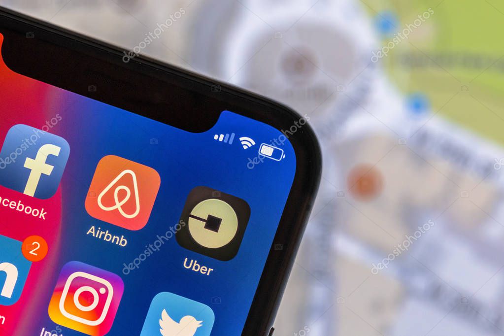 NEW YORK, USA - NOVEMBER 8, 2017: Uber app logo on modern mobile phone with street map in the background. Airbnb is an online marketplace offering people a service to rent short-term lodging.