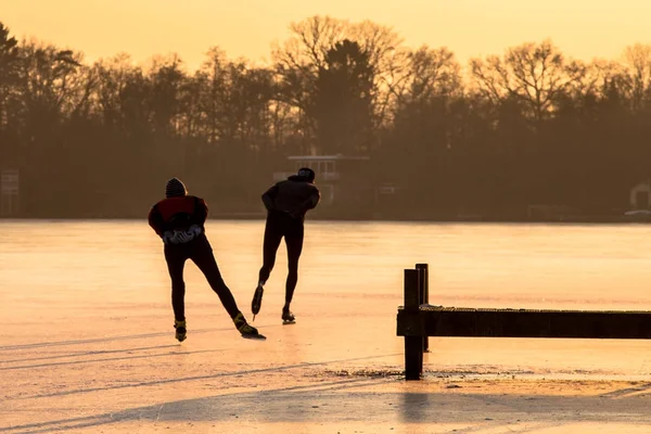 Siluetas de patinaje de velocidad de hielo en luz naranja — Foto de Stock