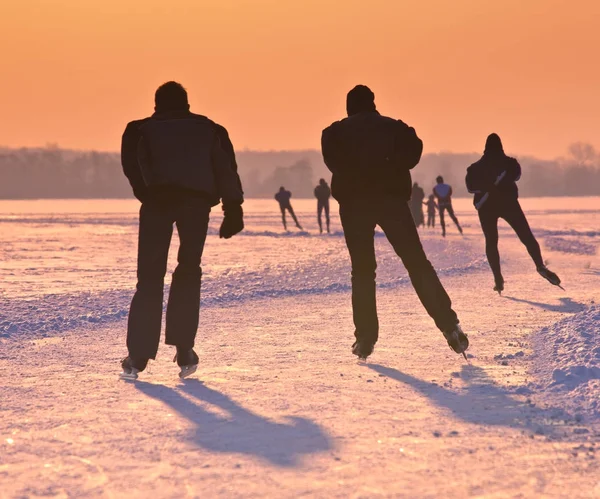 Patinadores de hielo en el lago congelado al atardecer — Foto de Stock