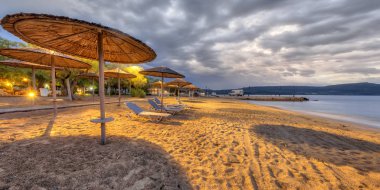 Alacakaranlık boş plajda Reed şemsiye