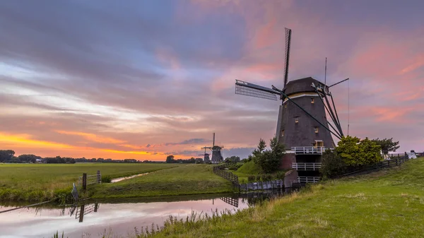 Three windmills in a row under beautiful sunset — Stock Photo, Image