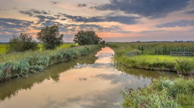Kanal geçiş tipik Hollanda tarım manzara renkli günbatımı gökyüzü altında