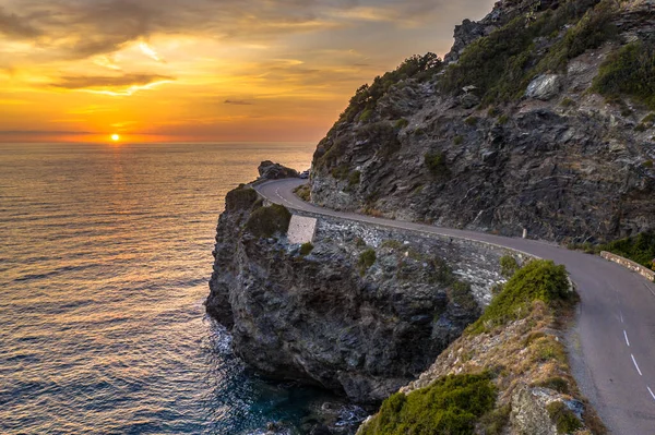 Günbatımında, Fransa 'nın Korsika adasındaki Cap Corse yarımadasının kayalık kıyılarında dolambaçlı yol.
