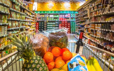 Süpermarketteki market arabası müşterilerin bakış açısından bakılan gıda ürünleriyle dolu.