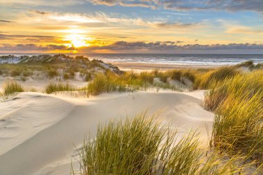 Hollanda, Ameland adasından, Kuzey Denizi 'nde gün batımının üzerindeki kum tepesinden manzara