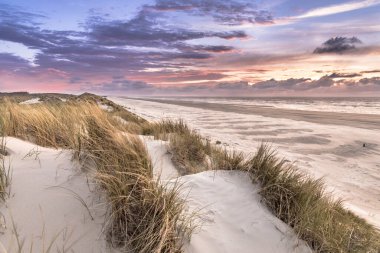Hollanda, Ameland adasından, Kuzey Denizi 'nde gün batımının üzerindeki kum tepesinden manzara