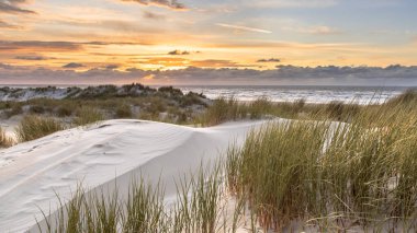 Hollanda, Ameland adasından, Kuzey Denizi 'nde gün batımının üzerindeki kum tepesinden manzara