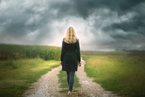 Üzgün bir kadının kırsal bir yolda tek başına yürümesi..