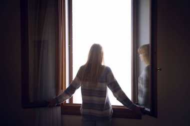 Kadın açık pencerede duruyor.