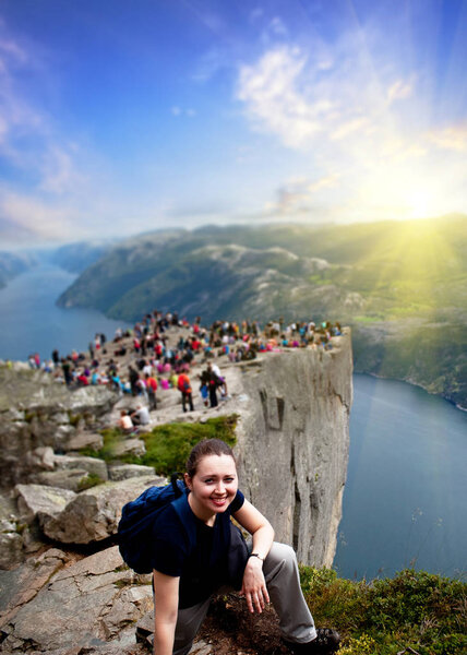 A girl resting on in Norway mountains , with people on a Preacher's Pulpit Rock of a Lysefjord on a background