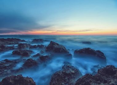 Günbatımı ve kayalarda sakin deniz suyu ile deniz manzarası