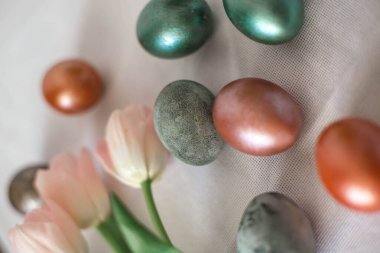 Beyaz tabakta güzel renkli, parlak paskalya yumurtaları. Pembe laleler çiçek buketi. Mutlu Paskalyalar.