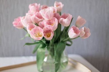 Bir buket bahar çiçeği cam vazoda güzel çiçekler. Beyaz arkaplanda taze pembe laleler.