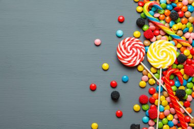Renkli şekerler ve gri arka plan üzerinde lolipop. Kopya alanı ile Üstten Görünüm