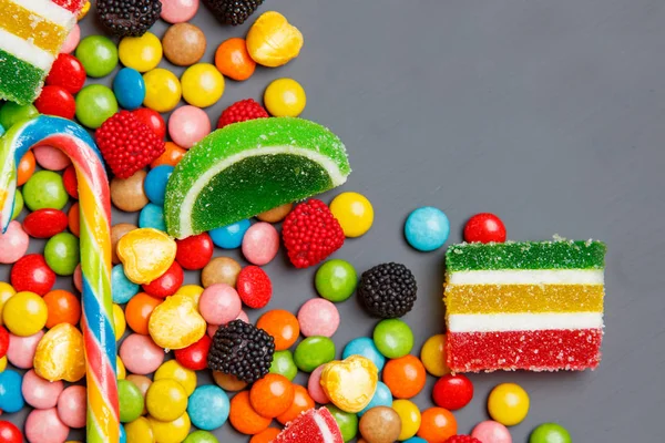 Colorful candies and lollipops over stone background. Top view with copy space — Stock Photo, Image