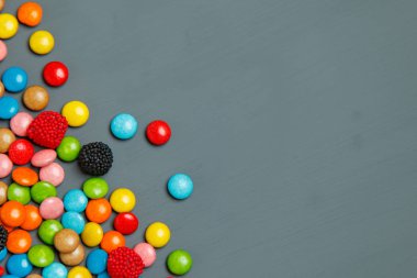 Gri bir ahşap masa üzerinde renkli şekerler