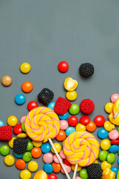 Mix gri ahşap arka plan üzerinde renkli lolipop, şekerler ve tatlı şekerler — Stok fotoğraf
