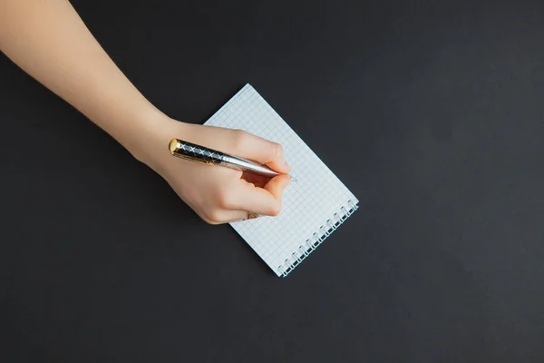 Mujer escribiendo en bloc de notas en mesa negra — Foto de Stock