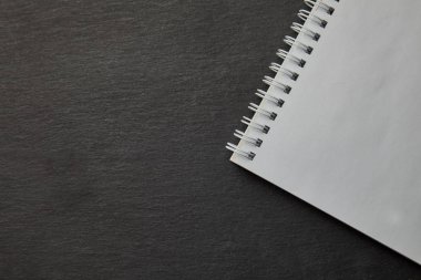 Siyah masa üstünde boş beyaz spiral defter. Üstten Görünüm.