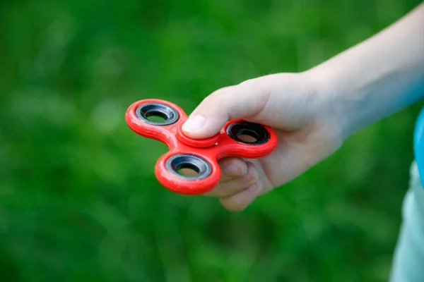 Fechar fidget spinner vermelho na mão. Dispositivo giratório popular — Fotografia de Stock