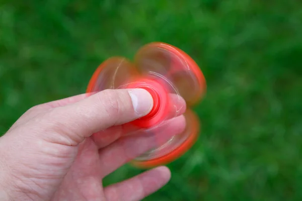 Fechar fidget spinner vermelho na mão. Dispositivo giratório popular — Fotografia de Stock