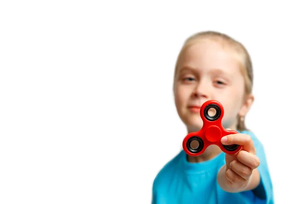 Pequeña chica hermosa en azul camiseta está jugando rojo spinner en la mano —  Fotos de Stock