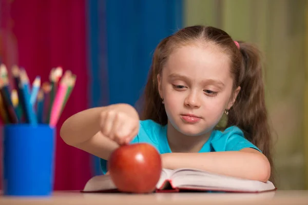Retrato de una linda chica feliz sosteniendo una manzana roja en el aula —  Fotos de Stock