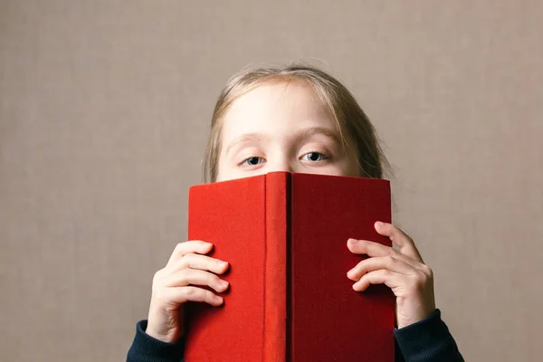 Beau bébé couvrant son visage avec un livre . — Photo