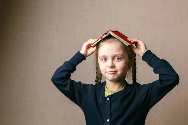 Kleines Mädchen mit einem Buch über dem Kopf — Stockfoto