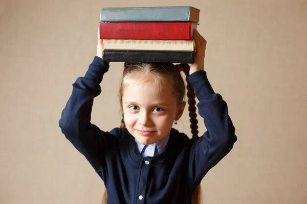 Schattig klein meisje met boeken over haar hoofd — Stockfoto