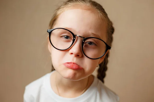 Triste niña en gafas está mirando con cara seria en la cámara —  Fotos de Stock