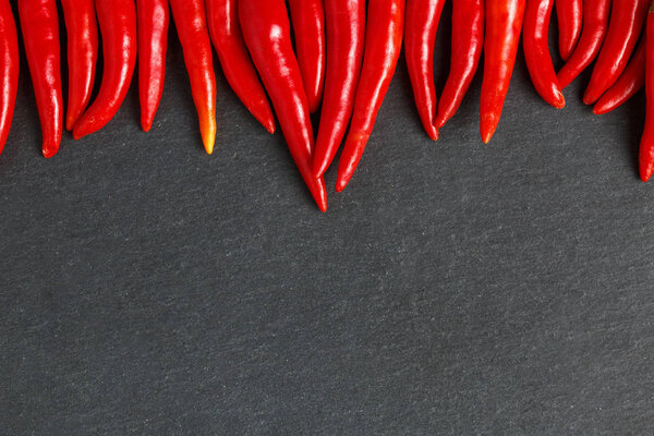 Slate background with red hot chilli peppers. Concept for chilli peppers lovers