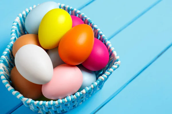 Huevos coloridos de Pascua en la cesta aislados sobre un fondo azul —  Fotos de Stock