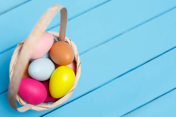 Huevos coloridos de Pascua en la cesta aislados sobre un fondo azul —  Fotos de Stock