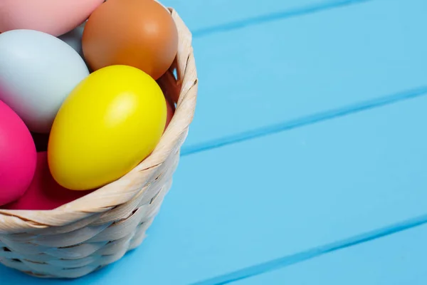 Huevos de Pascua en la cesta sobre fondo de madera azul —  Fotos de Stock
