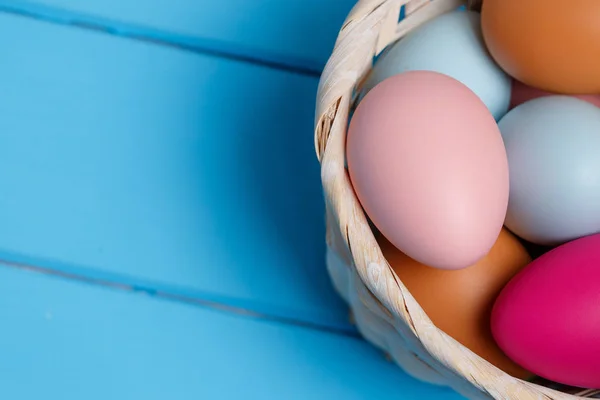 Huevo de Pascua colorido en la cesta sobre fondo de madera azul con espacio . —  Fotos de Stock