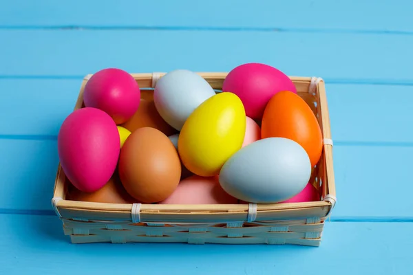 Huevos de Pascua en la cesta sobre fondo de madera azul —  Fotos de Stock