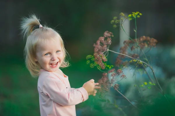 Gelukkig klein meisje lachen plant achtergrond buiten — Stockfoto