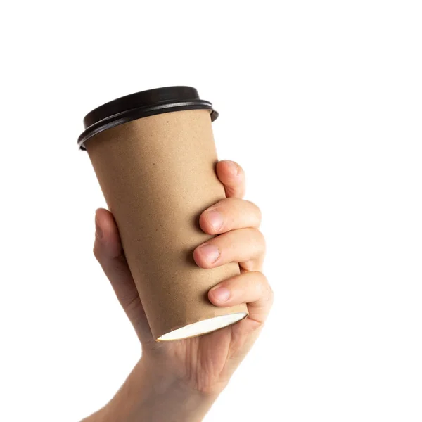 Uomo mano tenendo marrone tazza di carta di caffè con coperchio nero isolato su sfondo bianco . — Foto Stock