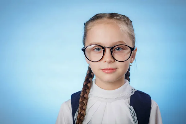 Retrato de una encantadora colegiala en gafas sobre un fondo azul —  Fotos de Stock